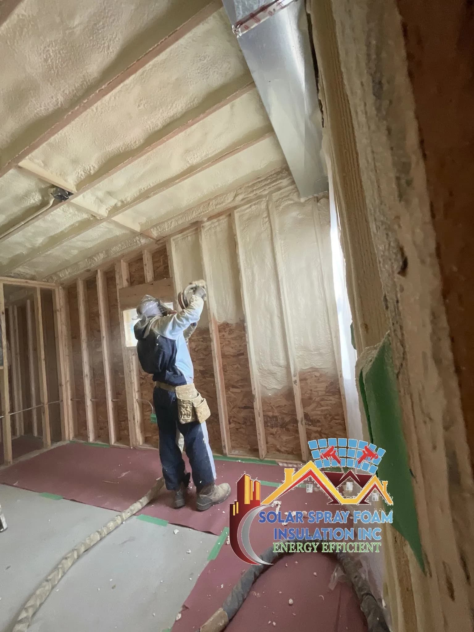 Solar Spray Foam Insulation technician in full protective equipment applying spray foam insulation to a wall in Elgin, IL