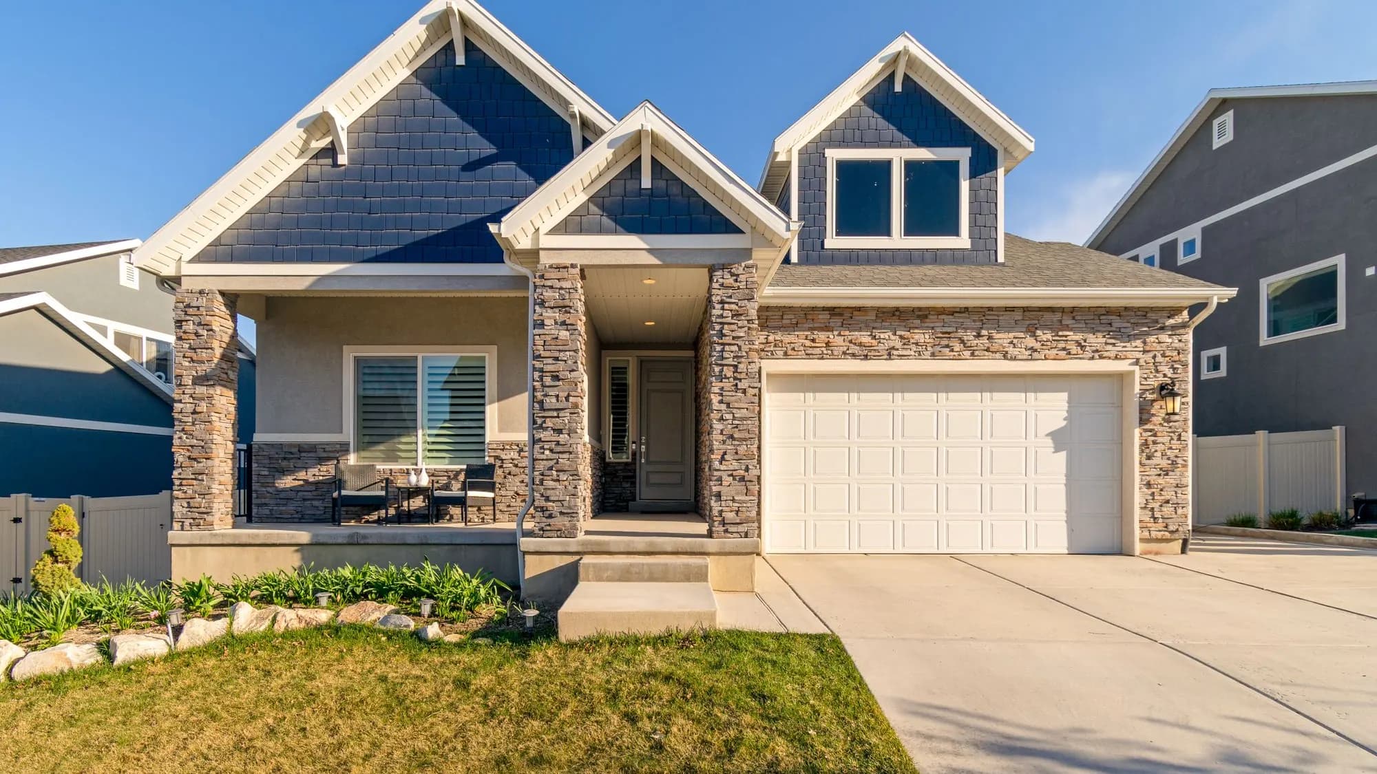 American family home with a stone and shingle facade, an open porch and an attached garage