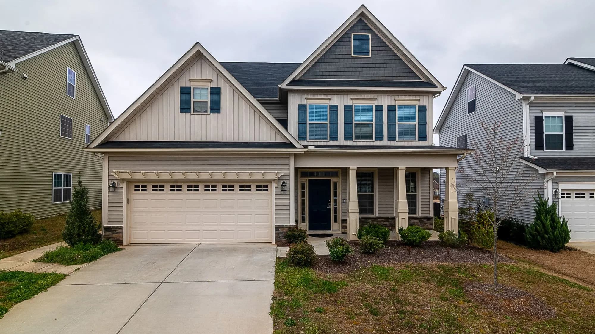 Brick and siding family home with an attached garage on a tree-lined street — the kind of home we insulate in Elburn, IL