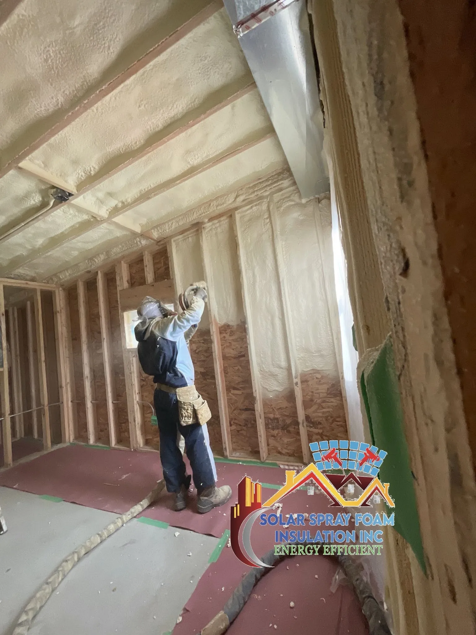 Solar Spray Foam Insulation technician in full protective equipment applying spray foam insulation to a wall in Elgin, IL